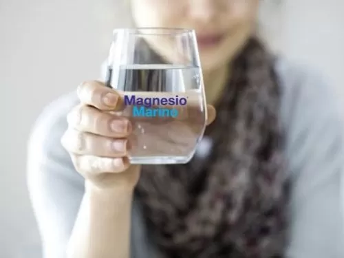 Donna che breve un bicchiere d'acqua con una bustina di Magnesio Marino®